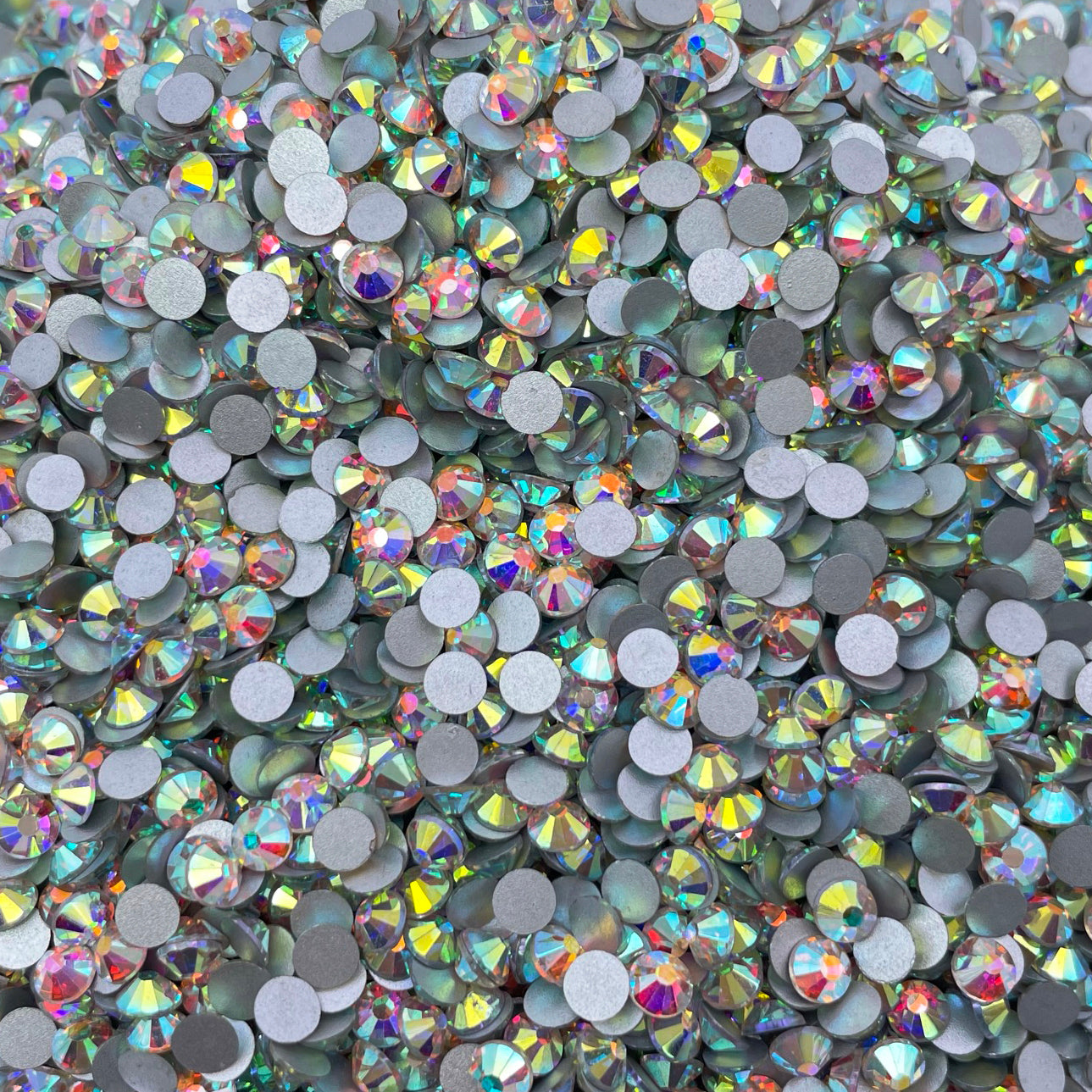 Many silber rhinestones together in a pile, reflecting different colors.