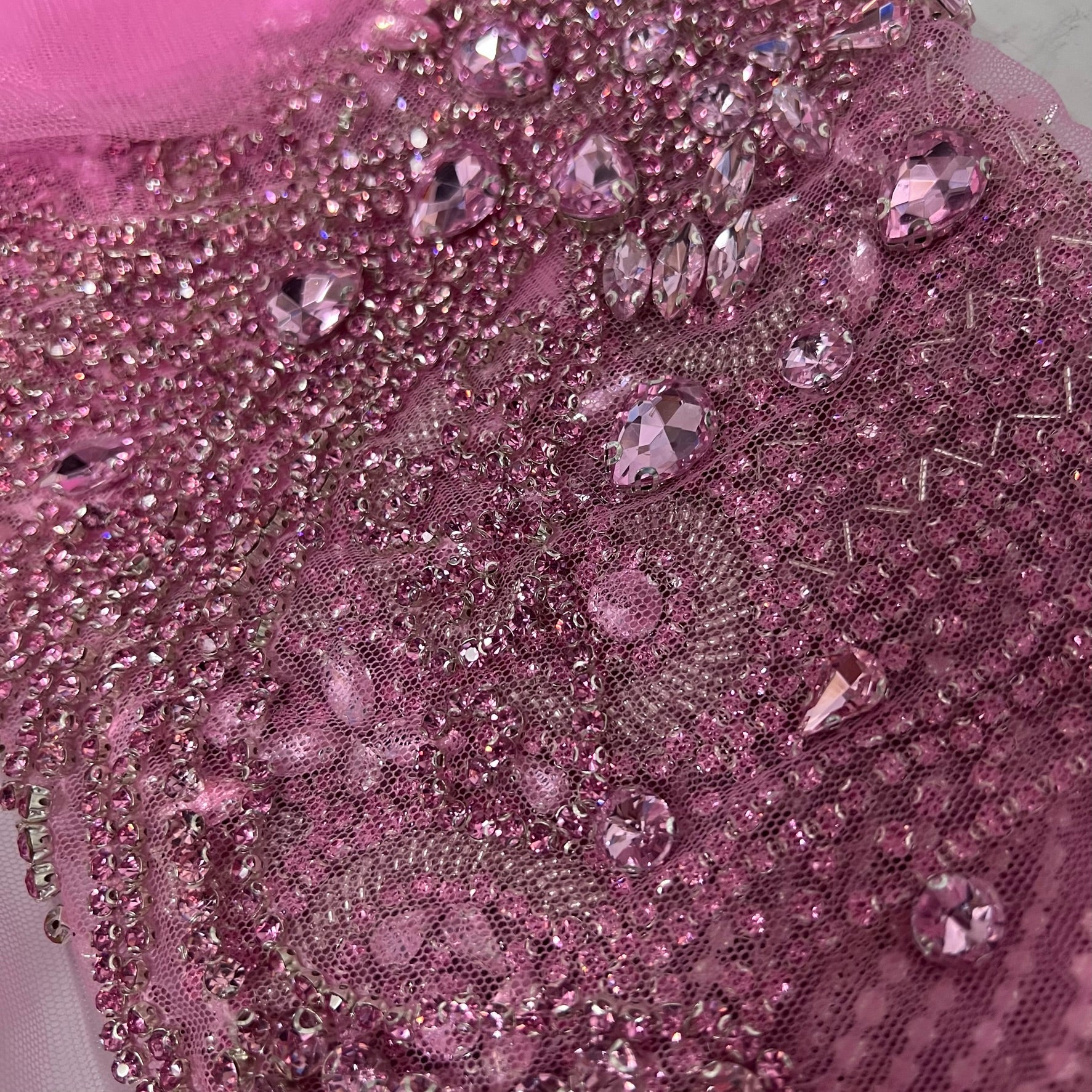 Many pink rhinestones on a pink net material.