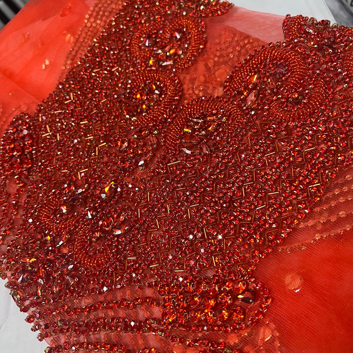 Many red rhinestones on a red net material.