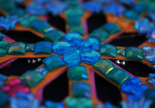 Close-up of a colorful floral rhinestone design with blue and green gems.