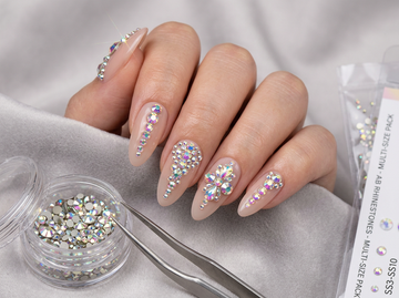 Nude almond nails decorated with iridescent rhinestones in floral and cascading designs.