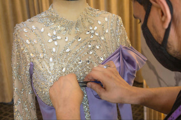 Designer adding rhinestones to embellished gown bodice