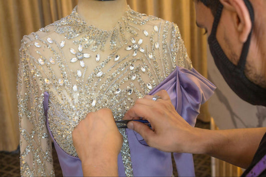 Designer adding rhinestones to embellished gown bodice