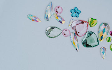 Rhinestones in various shapes and colors strewn across a white countertop.