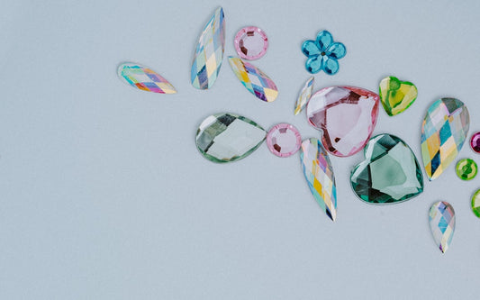 Rhinestones in various shapes and colors strewn across a white countertop.