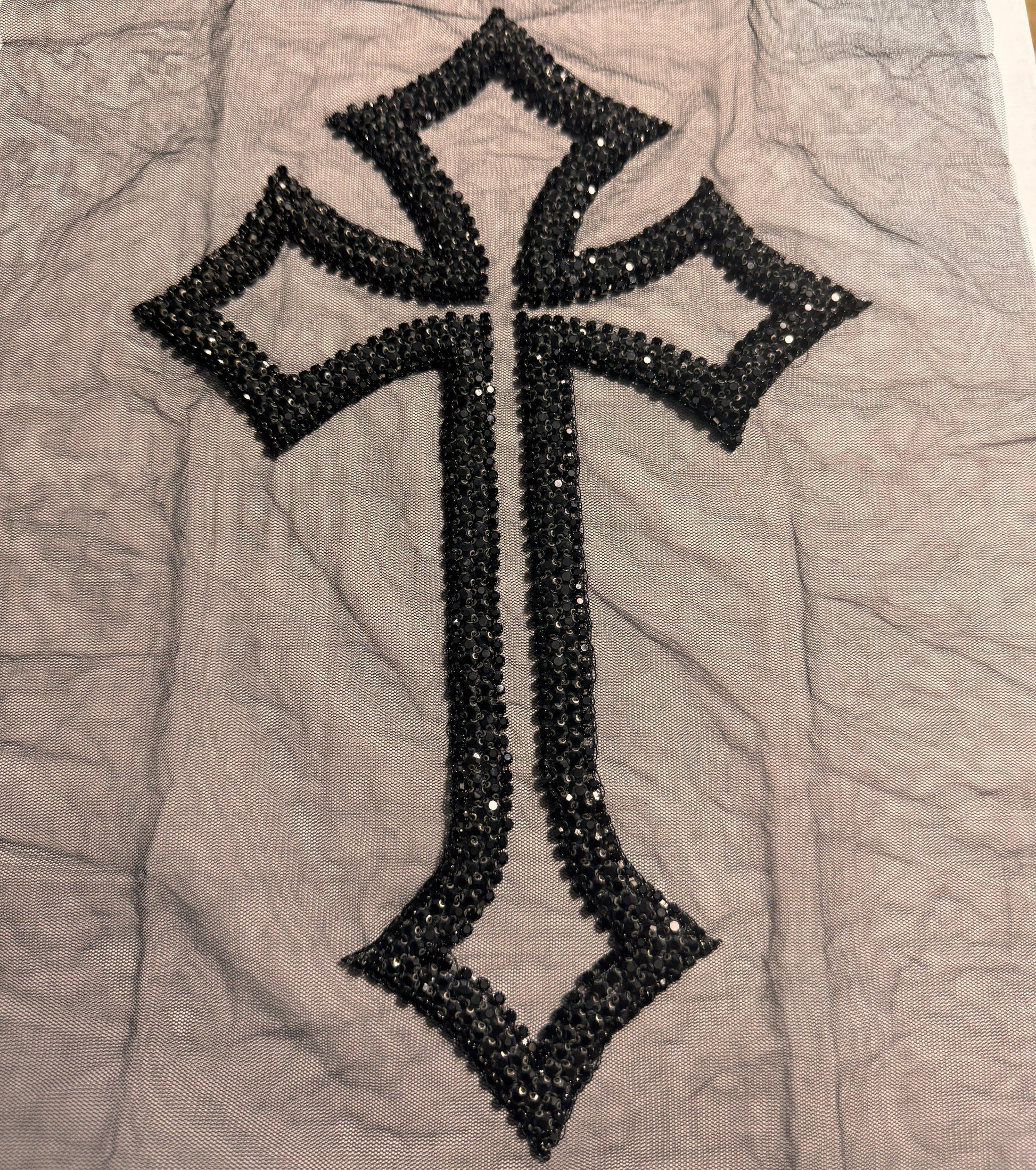Black cross design with sequins on a gray fabric background