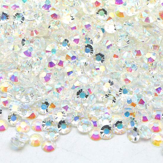 Many white rhinestones together in a pile, reflecting different colors.