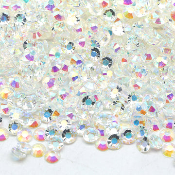 Many white rhinestones together in a pile, reflecting different colors.